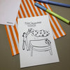 Eine Grußkarte mit der Aufschrift "Meine Sorgen möcht ich haben." liegt auf einer orange-weiß gestreiften Papiertüte, daneben liegen zwei Stifte.