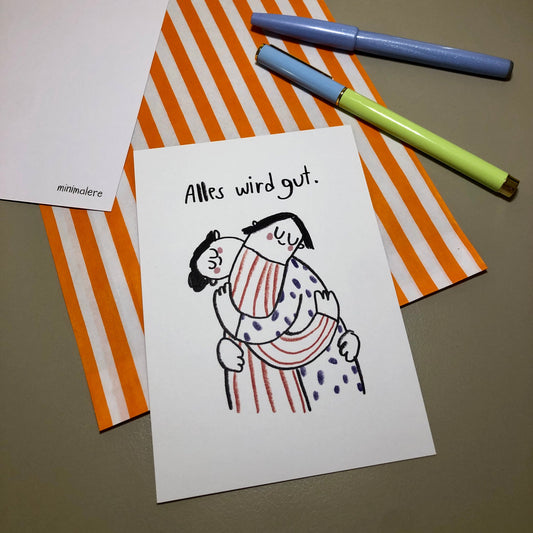 Eine Grußkarte mit der Aufschrift "Alles wird gut." liegt auf einer orange-weiß gestreiften Papiertüte, daneben liegen zwei Stifte.